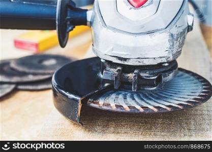 Electric cutting and grinding machine. Angle grinder with abrasive disc on wooden boards. The concept of tools and repair work.. Electric cutting and grinding machine. Angle grinder with abrasive disc on wooden boards.