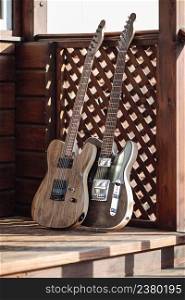 Electric guitars are leaned against a wooden stairs outside on the terrace