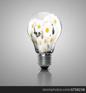 Electric light bulb and flower inside it as symbol of green energy