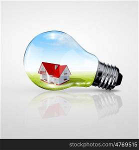 Electric light bulb and house inside it as symbol of green energy