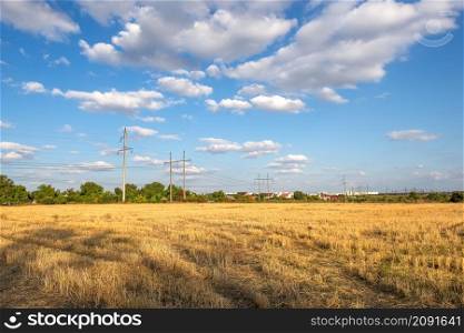 Electric poles on field of mown wheat in countryside. Electric poles on field