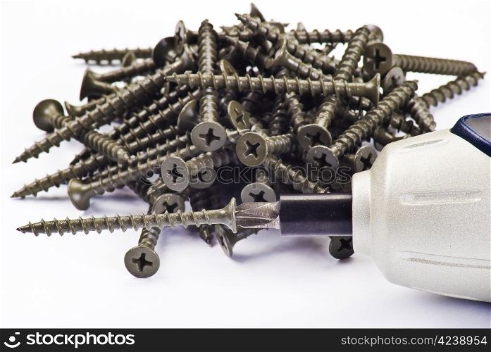 Electric screwdriver and screws over white background
