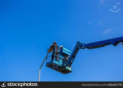 Electric technical repairing street light by boom lift in industrial