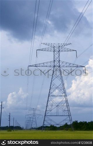 Electric tower poles on a green meadow over sky
