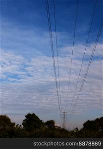 electric wires on a pylon in the distance spreading across the clear blue and cloudy sky beautiful communication peace