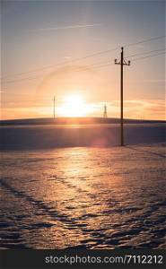 Electrical tower on a snowy field in Austria, sunset scenery