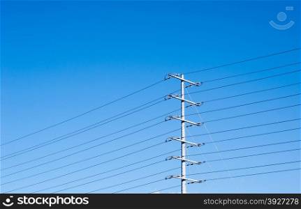Electrical tower with multiple levels of parallel power lines and insulators, on clear blue sky background and copy space at top.