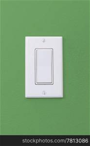 Electrical white rocker light switch on green wall