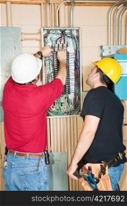 Electrician and apprentice changing out a faulty circuit breaker in an industrial panel.