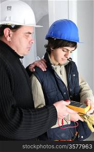 Electrician and his apprentice with a multimeter
