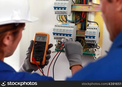 electrician and his apprentice working on a fuse board