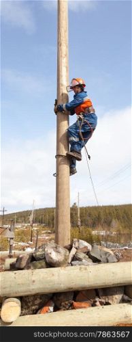 Electrician begins to climb on a power pole with a claw-Lazikans and safety belt