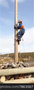 Electrician begins to climb on a power pole with a claw-Lazikans and safety belt