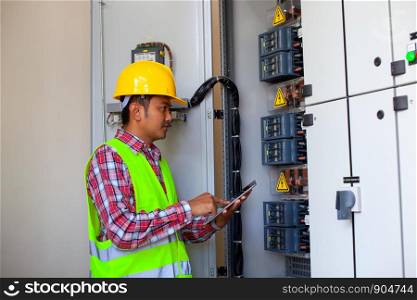 electrician builder at work with tester measuring high voltage and current of power electric line in electrical distribution fuse board. Focus on hands
