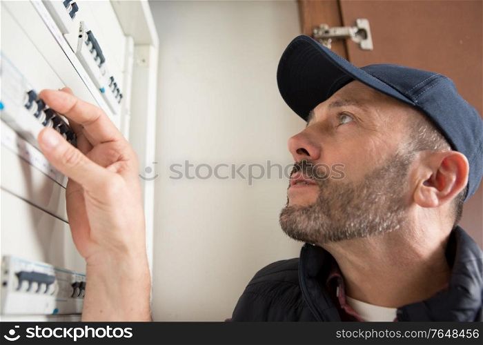 electrician checking fuses in circuit breaker box