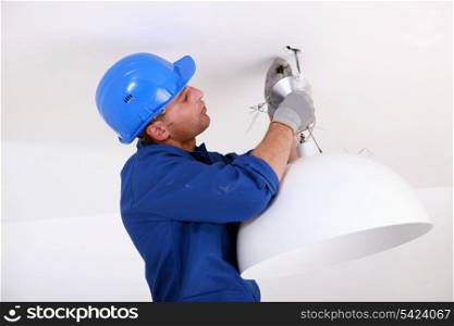 Electrician fitting a ceiling light