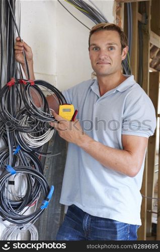 Electrician Fitting Wiring On Construction Site