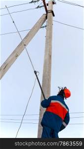 electrician in blue overalls establishes protective earth wire to the power line