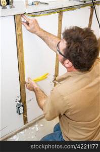 Electrician installing wiring in an interior wall. Authentic and accurate content depiction in accordance with industry code and safety standards.