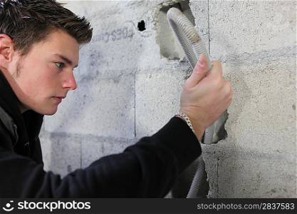 Electrician pulling conduit through a wall