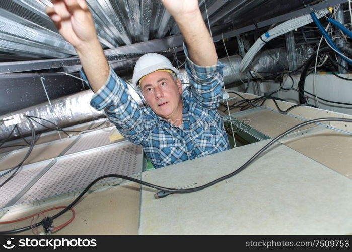 Electrician reaching into roof space