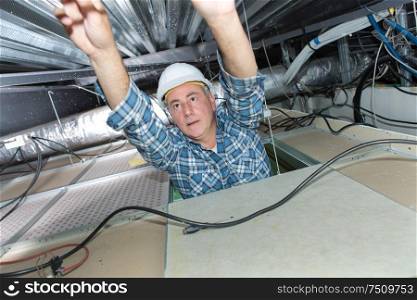 Electrician reaching into roof space