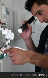 Electrician shining a torch on a fusebox