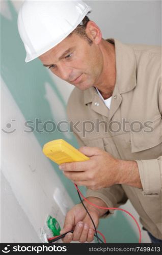 electrician technician fixes the electric cable to the socket