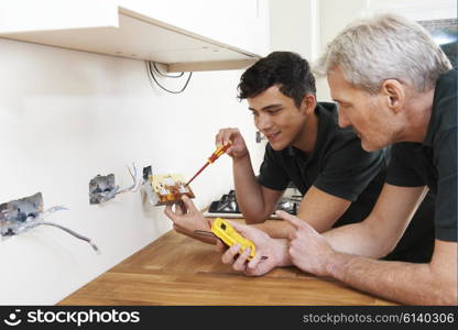 Electrician With Apprentice Working In New Home