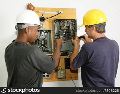 Electricians repairing breaker panel. Actual electricians performing work according to industry safety and code standards.