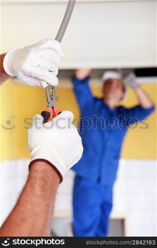 Electricians working on ceiling lighting