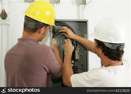 Electricians working together to install a breaker panel. Models are actual electricians - all work is performed according to industry standard code and safety practices.
