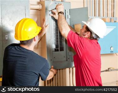 Electricians working together to repair an industrial circuit breaker panel.