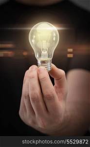 electricity and energy concept - close up of man hand holding light bulb