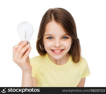 electricity, education and people concept - smiling little girl holding light bulb