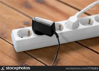 electricity, energy and power consumption concept - close up of socket with plugs and charger on wooden floor. close up of socket with plugs and charger on floor