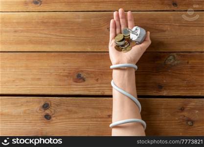electricity, energy crisis and power consumption concept - close up of hand wrapped with plug holding coins on wooden table. close up of hand wrapped with plug holding coins