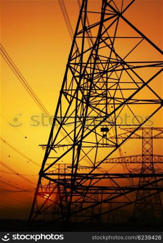 Electricity Pylon over orange sunset sky. Environmental damage