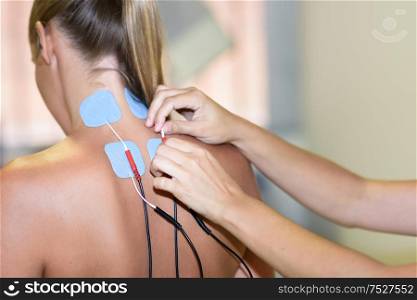 Electro stimulation in physical therapy to a young woman. Medical check at the shoulder in a physiotherapy center.. Electro stimulation in physical therapy to a young woman