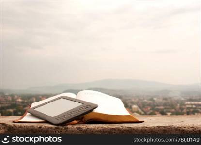 Electronic book reader laying on the book outdoors