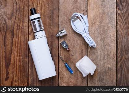 Electronic cigarette with coils, atomizer and heads on wooden table still life