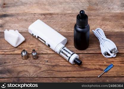 Electronic cigarette with coils, atomizer, heads and e-cigarette liquid on wooden table still life