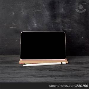 electronic tablet with a blank black screen and white pencil, copy space