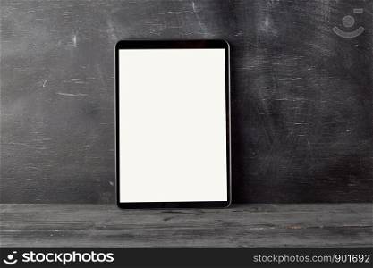 electronic tablet with a blank white screen against a black chalk board, copy space