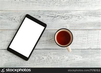 electronic tablet with a Cup of tea or coffee on a vintage shabby white wooden background. the view from the top. flat lay