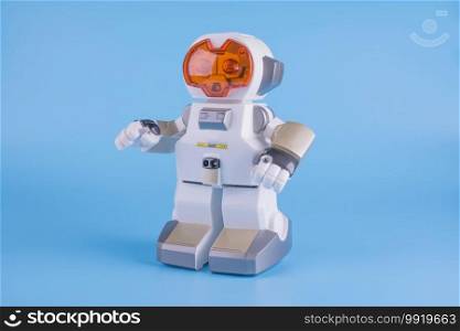 electronic, toy robot white with orange eyes on a blue background, close-up, side view. electronic, toy robot white with orange eyes