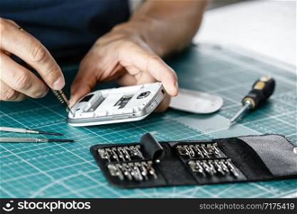 Electronics repair service. Technician disassembling smartphone for inspecting.. Electronics repair service. Technician disassembling smartphone for inspecting