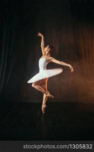 Elegance ballerina in white dress and pointe shoes dancing on theatrical stage. Classical ballet dancer training in class. Ballerina in white dress and pointe shoes dancing