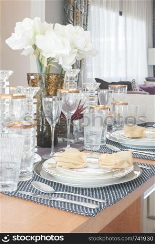 Elegance style dining table with golden trim glassware and white flower in the center of table