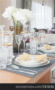 Elegance style dining table with golden trim glassware and white flower in the center of table